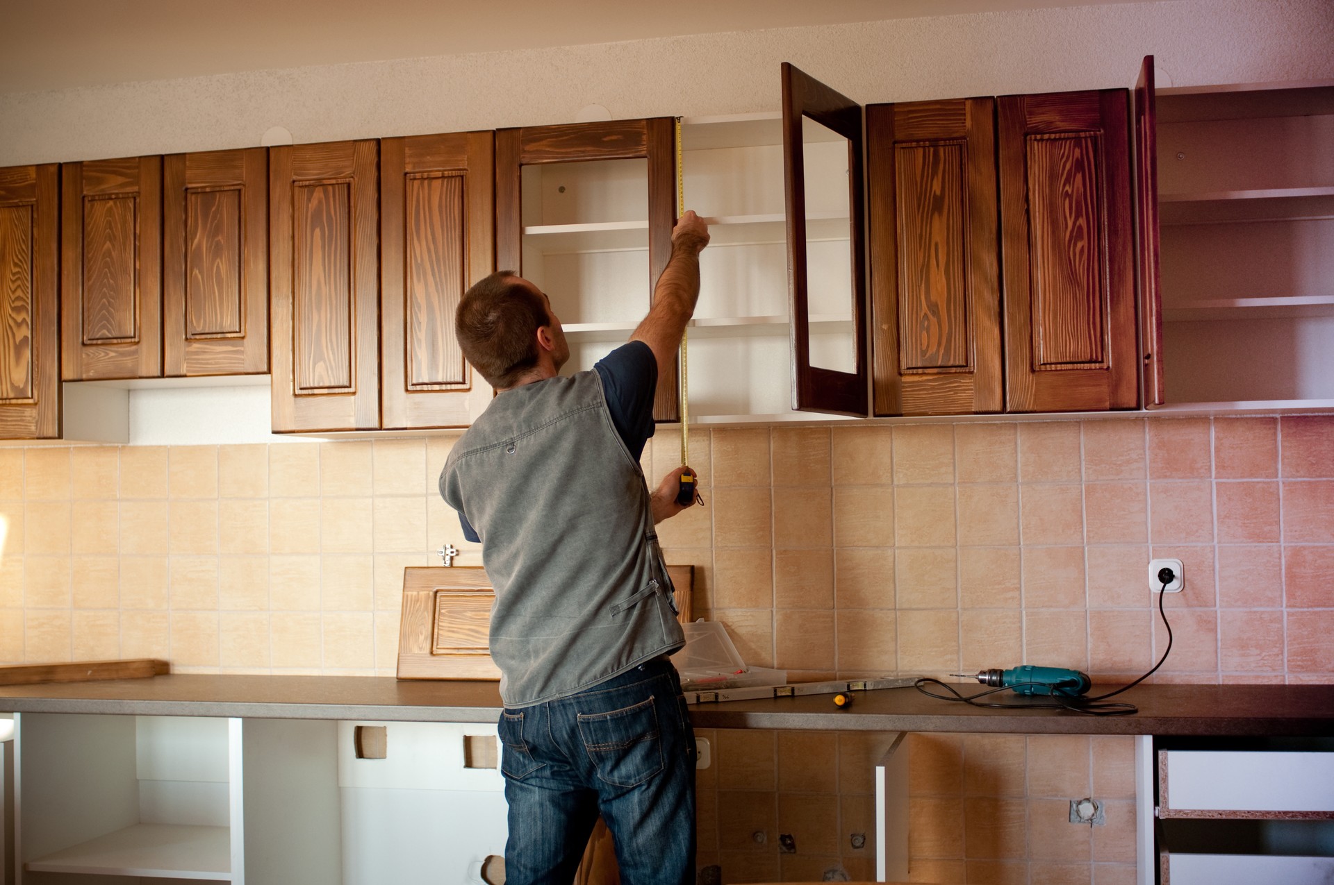 Man constructing cabinet units in new kitchen